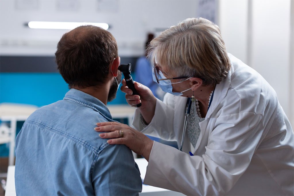 Doctor examining a patient's ear with an otoscope